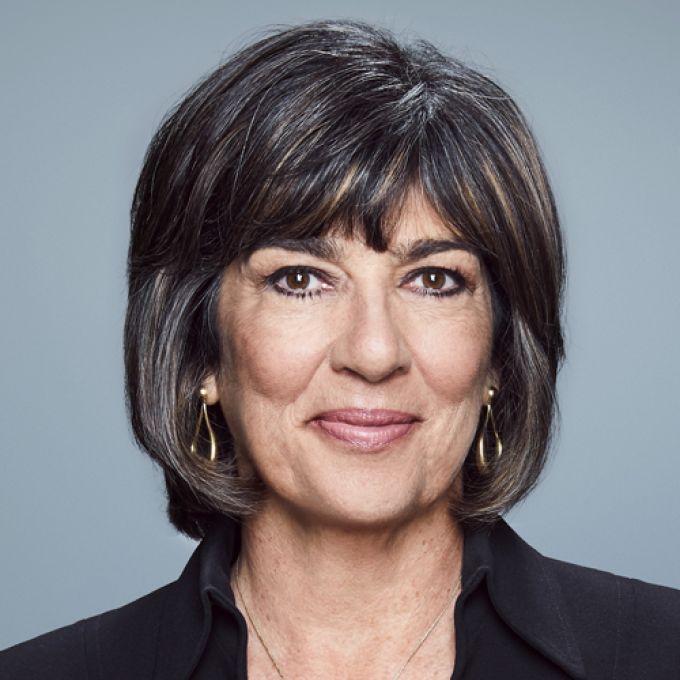 A woman with shoulder-length dark hair smiles in a dark jacket and white shirt