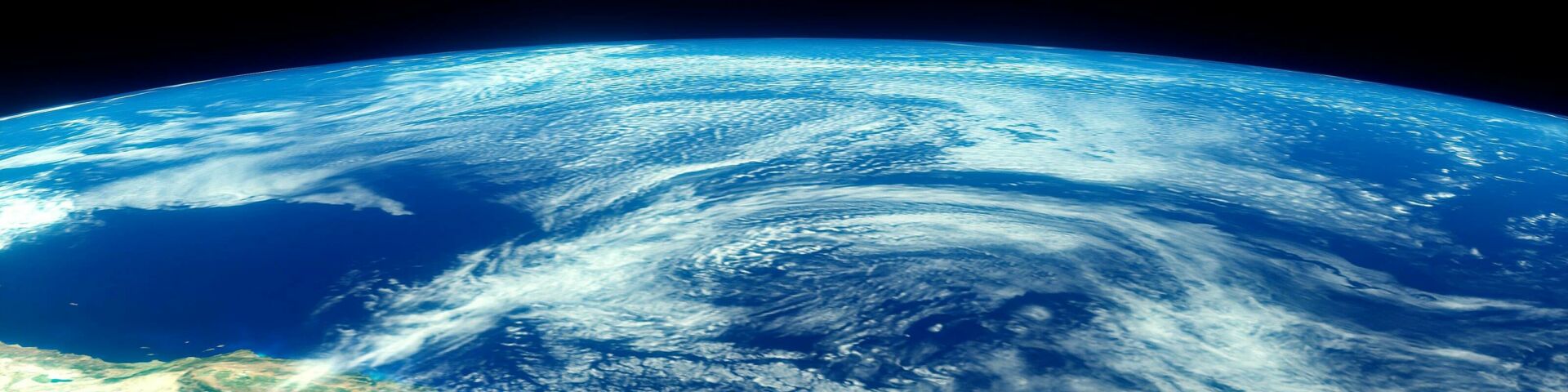 Part of earth shot from space with a small piece of a continent visible and swirling clouds above a deep blue ocean