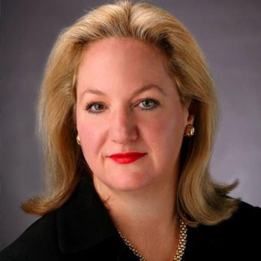 A woman with shoulder-length blonde hair poses in a black jacket